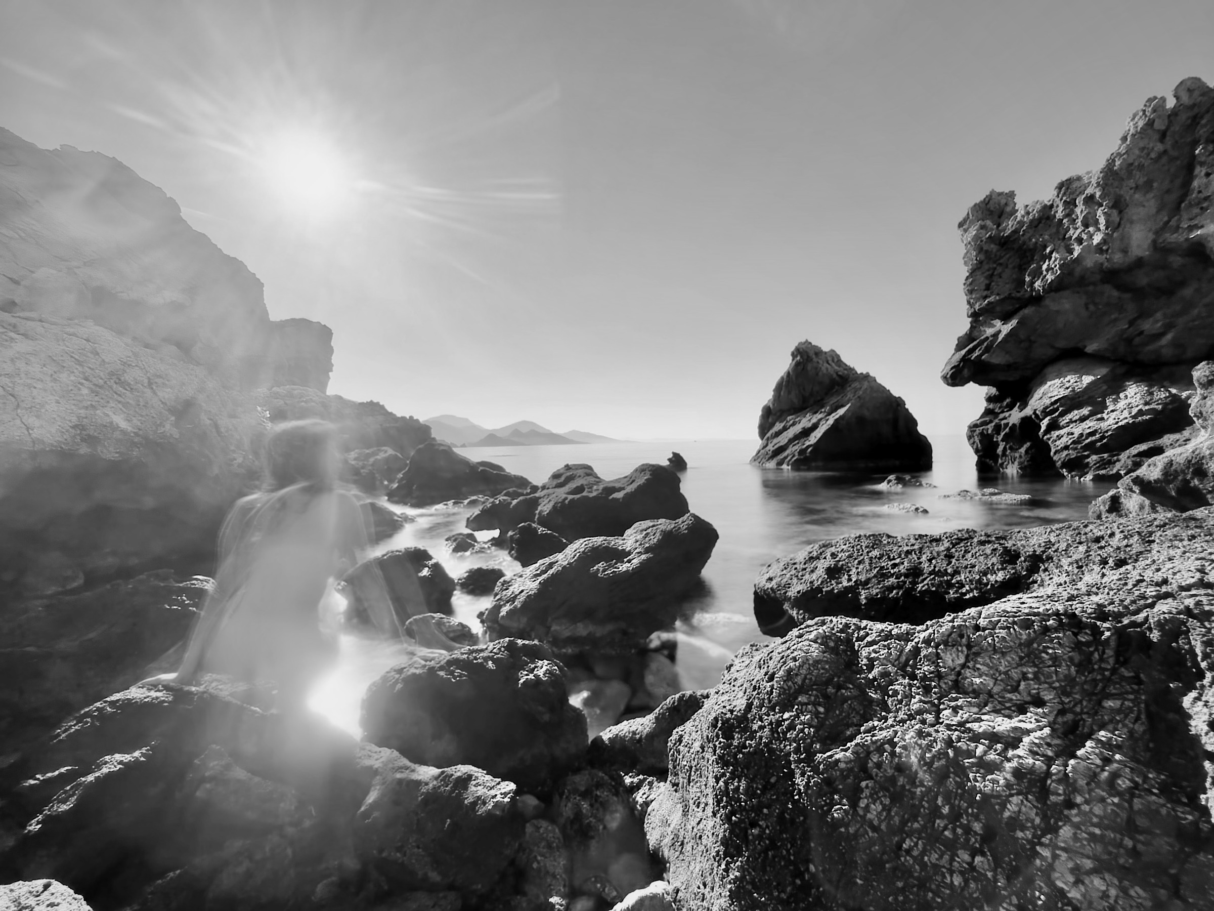 Zwart-wit long-exposure — figuur in zonneflare aan de Egeïsche kust